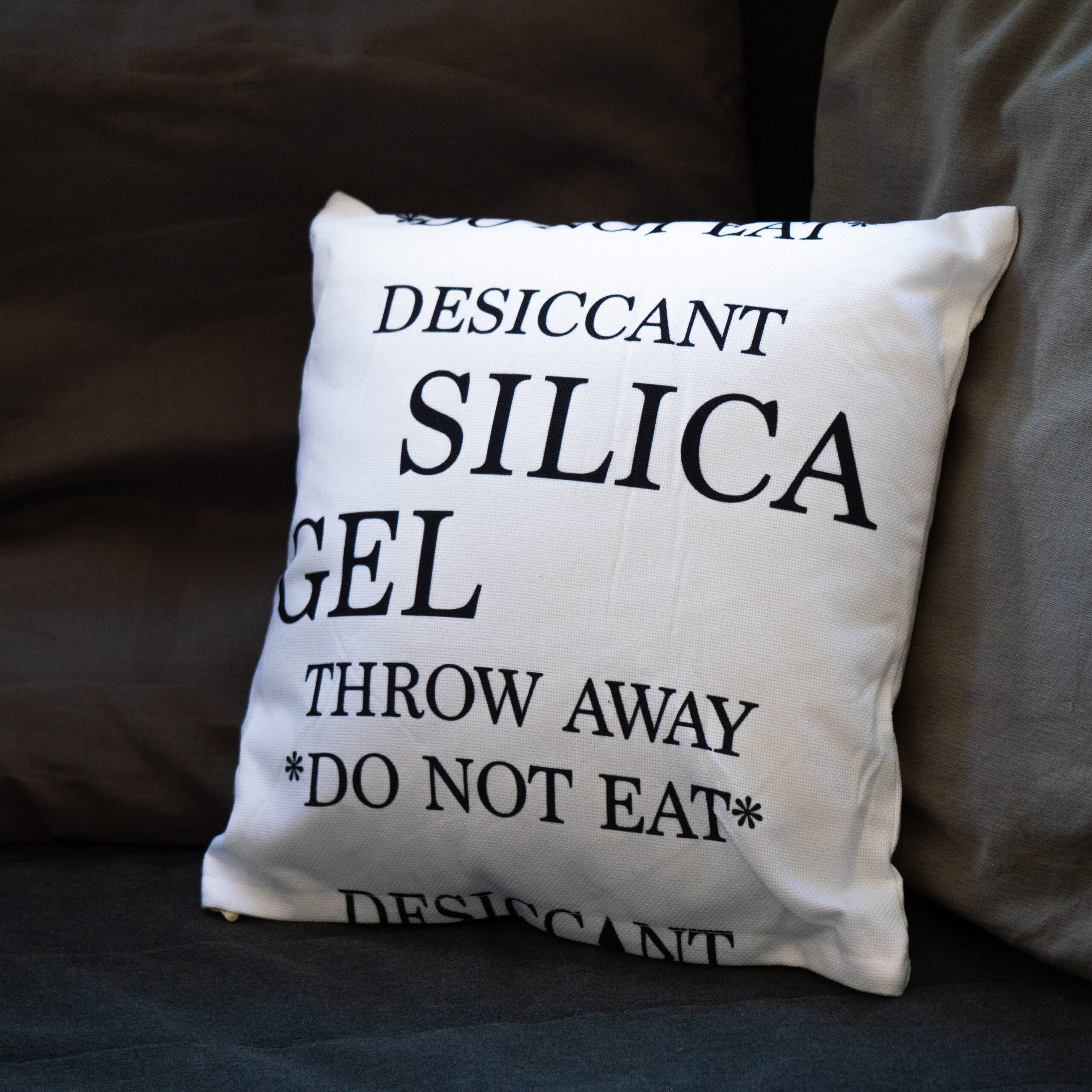 Weißes Sofakissen im Silica-Gel-Beutel-Design mit schwarzem Warnaufdruck
